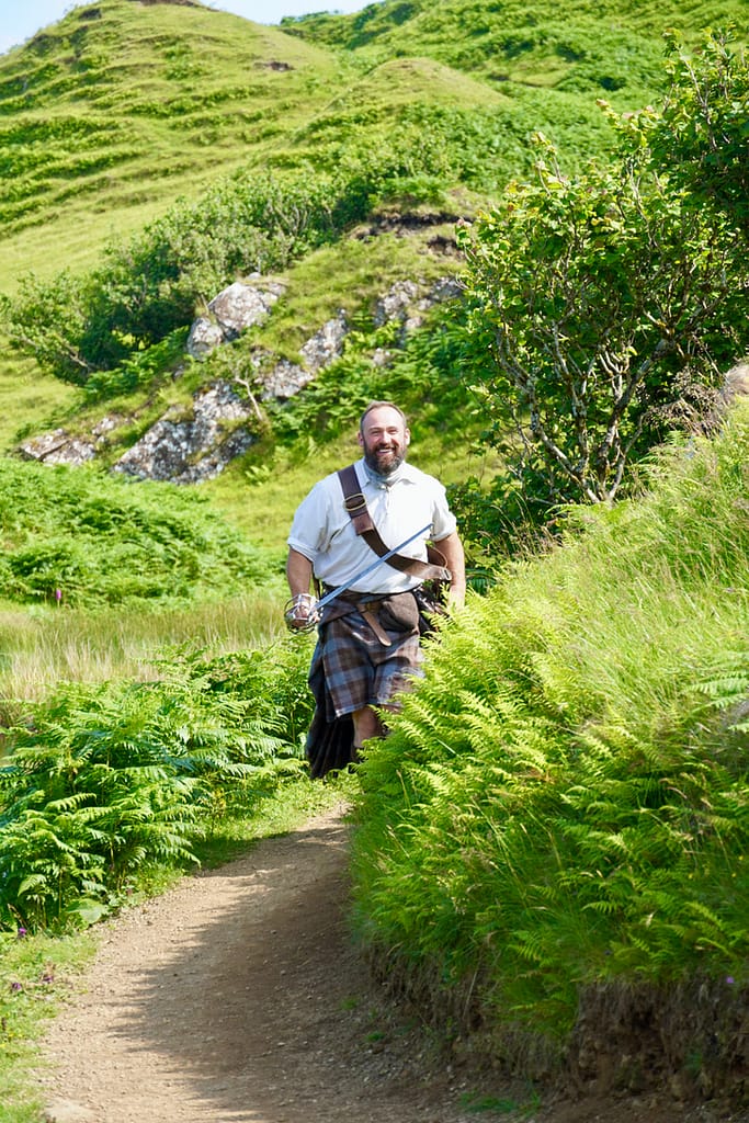 Andy the Highlander comes around the corner of the path at Castle Ewen