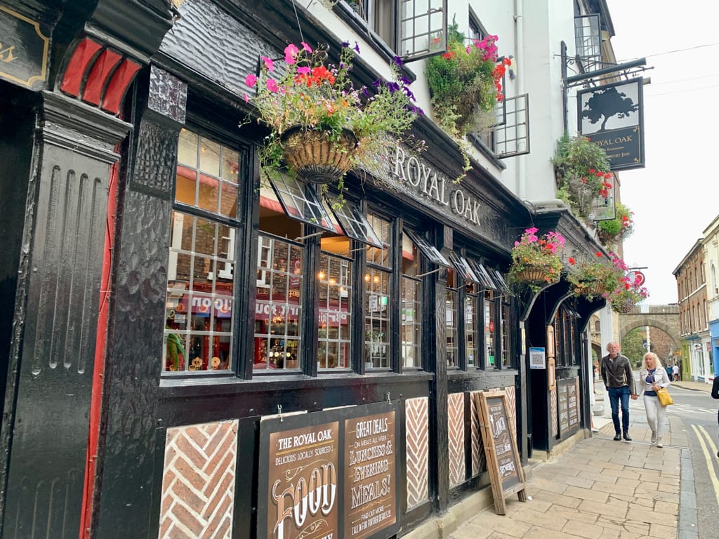 Royal Oak pub in York, England. The pub is built in red brick and black painted wood, and flower baskets line the front facade.